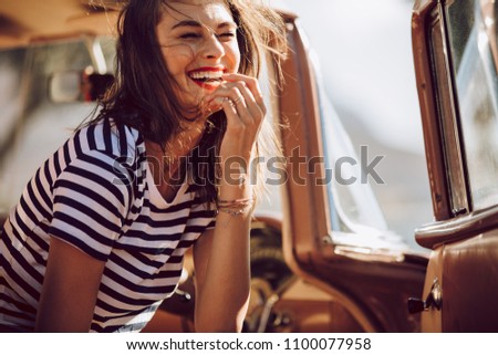 Beautiful woman sitting in a car and laughing. Woman having fun outdoors on the road trip.
