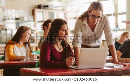 Portrait of young teacher helping a student during class. University student being helped by female lecturer during class.
