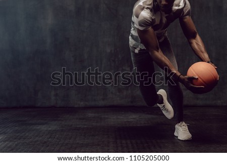 Athletic man training with a basketball. Man working out holding a basketball in hand.