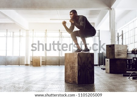 Man doing squats on a squat box at the gym. guy at the gym working out standing on a wooden squat box.