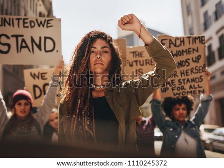 Woman leading a group of demonstrators on road. Group of female protesting for equality and women empowerment.