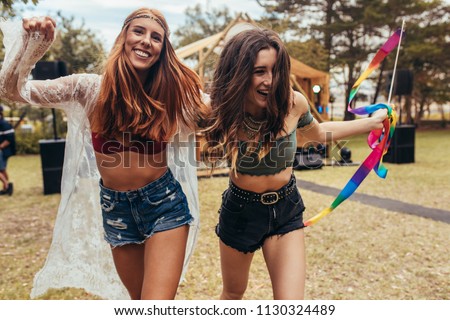 Hipster girls having fun at music festival outdoors. Two women enjoying at park during a summer festival.