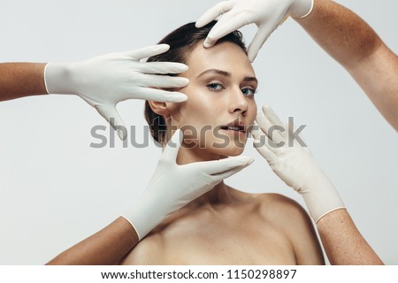 Beautician hands in gloves checking female face skin before aesthetic medical therapy. Woman going under cosmetic treatment on her facial skin.