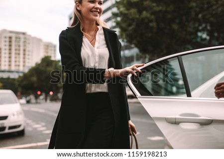 Smiling woman commuter getting out of a taxi. Businesswoman getting off a cab.