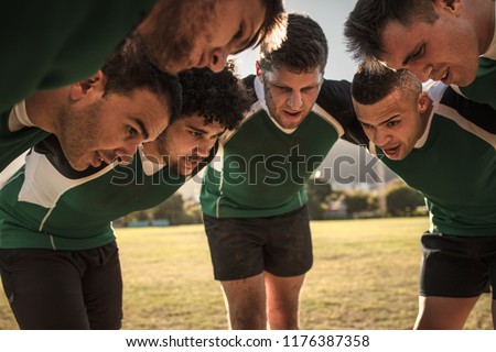 Team of rugby players in huddle discussing their tactics. Professional rugby team in huddle during the game.