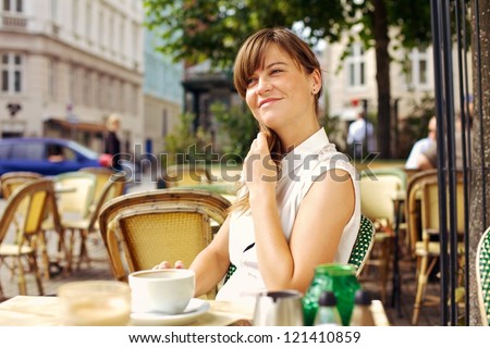 Woman enjoying the pleasant morning with a cup of coffee outdoors in a street cafe