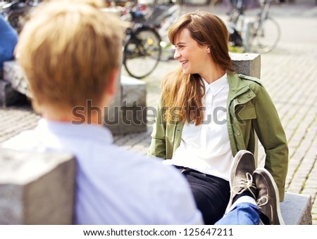 Attractive relaxing woman sitting on a park bench together with her boyfriend enjoying the pleasant morning