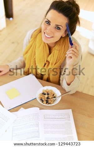Multitasking student having her breakfast while studying
