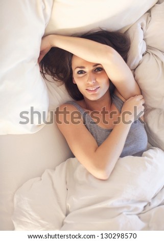 Beautiful woman lying on snowy bed waking up to a great morning