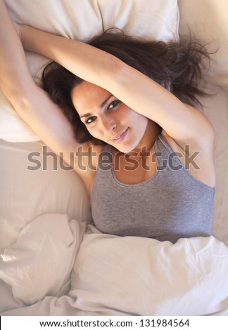Lazy morning woman lying on bed stretching her arms