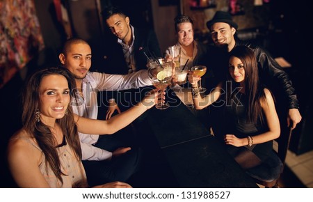 Group of friends at the bar raising their glass for a toast
