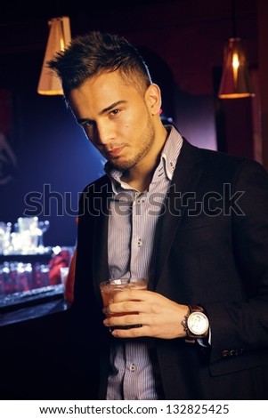 Handsome man alone at the bar with a glass of whiskey