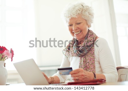 Old woman happy doing her shopping online using a credit card
