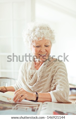 Old lady at home smiling while reading the news