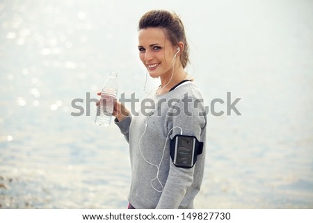 Happy female runner smiling while holding a bottled water