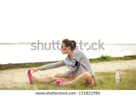 Active Female runner stretching before doing her summer fitness run