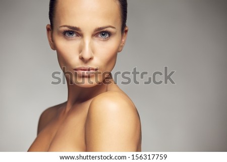 Beauty portrait of a beautiful caucasian young woman with perfect face skin isolated against gray background