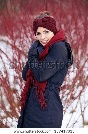 Shivering woman with red scarf in a cold winter park