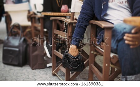 Man stealing wallet from the woman\'s purse at street cafe during daytime. Pickpocketing at the street cafe