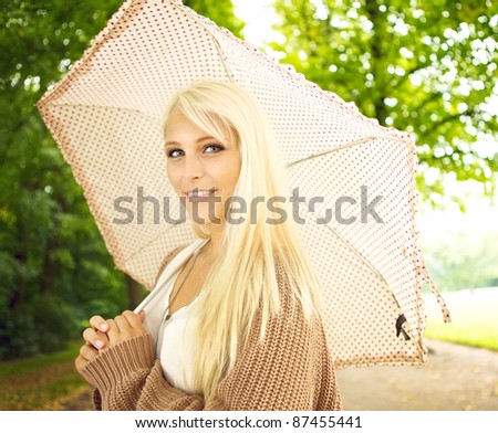 stock photo Beautiful busty young blonde girl with umbrella under trees in
