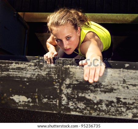 Determination on the face of a traceur climbing the wall of a high industrial building while demonstrating parkour