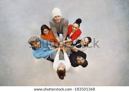 Group of happy young students showing. Top view of multiethnic group of young people putting their hands together. Young students standing in a circle making stack of hands showing unity as a team.