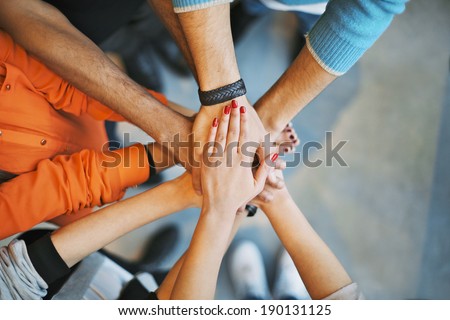 Closeup of stack of hands. Young college students putting their hands on top of each other symbolizing unity and teamwork.