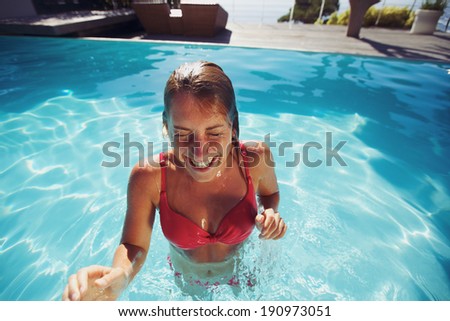 Young woman enjoying herself in a pool. Cheerful caucasian female wearing bikini in swimming pool.