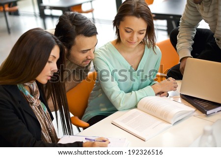 Group of students studying in a library. Young people sitting together at table working on school assignment.