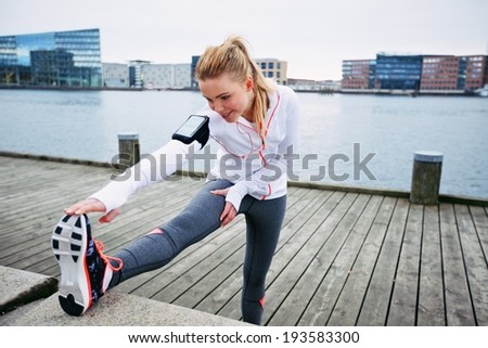 Fit young woman stretching before a run. Young female runner stretching her muscles before a training session