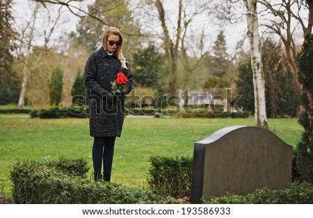 Young woman visiting a loved one at the cemetery paying respects with fresh rose flowers Female grieving at graveyard Young woman visiting a loved one at the cemetery paying respects with fresh rose flowers Female grieving at graveyard