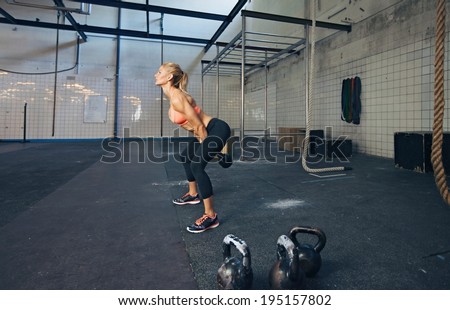 Young fitness female exercise with kettle bell. Caucasian woman doing crossfit workout at gym.