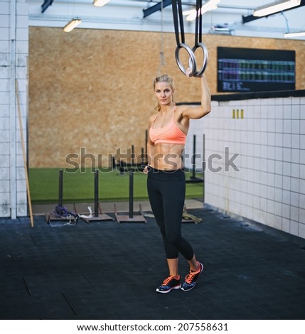 Attractive female model holding gymnast rings. Young caucasian woman at gym with rings.