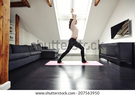 Fit young woman doing yoga at home. Healthy female model exercising in living home.