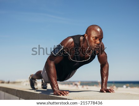 Young athletic man doing push-ups. Fitness model doing outdoor workout. Muscular and strong guy exercising.