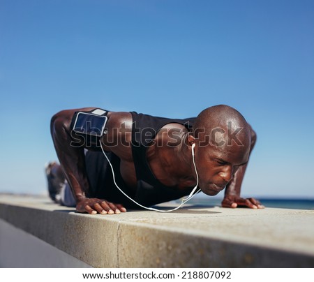 Image of sporty man doing push-ups. Strong young fitness model exercising. African male model workout outdoors.