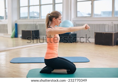 Side view fitness woman in gym exercising on workout mat. Caucasian female fitness model in gym.