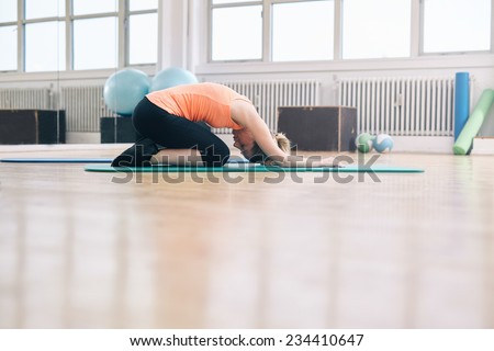 Portrait of woman doing a forward bend yoga exercise. Fitness woman practicing yoga at gym. Balasana - Child pose.