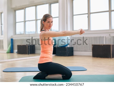 Gym woman working out doing stretch training and looking at camera. Fitness model training in health club.