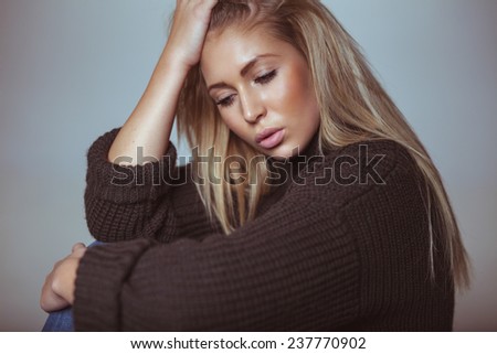 Contemplative young woman in sweater. Pretty young woman looking down in thought.