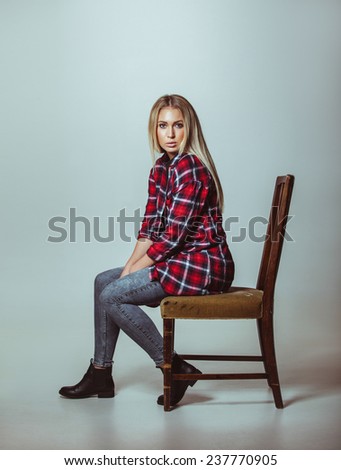 Portrait of beautiful young woman in casual outfit sitting on chair. Caucasian female model looking at camera.