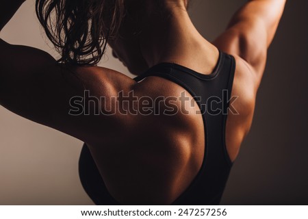 Close-up shot of back of female fitness model. Young woman in sports wear with muscular body.