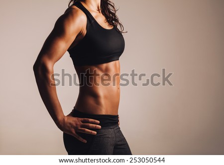 Cropped shot of fit woman\'s torso with her hands on hips. Female with perfect abdomen muscles.