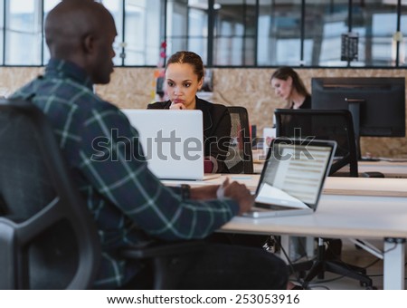 Young african woman sitting at her desk working on laptop computer. Businesswoman looking at laptop screen.