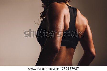 Back of a fit and muscular woman athlete in sports bra. Rear view of fitness female with muscular body. Highlighted on back.
