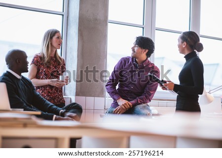 Team young professionals having casual discussion in office. Executives having friendly discussion during break.