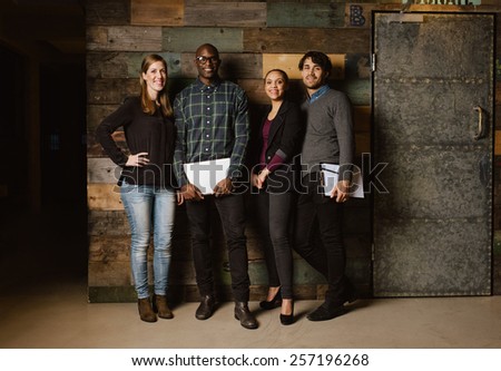 Full length portrait of successful business team standing in an office. Multiracial business professional posing for camera.
