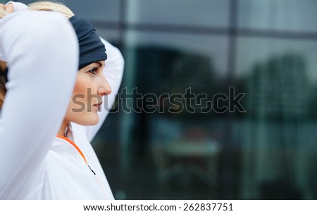 Side view of attractive female athlete ready of a run in city. Confident and motivated fitness woman looking away.