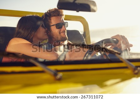Romantic young couple sharing a special moment while on a road trip. Man driving car with girlfriend.