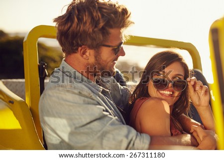 Portrait of romantic young couple having fun on a road trip. Playful young man and woman in a car on holiday.